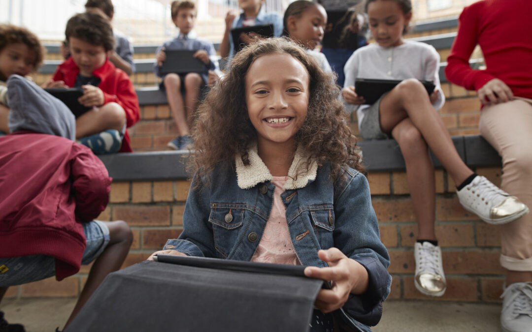 Confident young female student on tablet practicing digital citizenship in school commons area