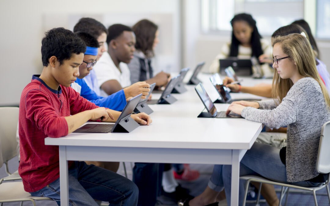 Group of students at table in school with tablets as online safety at school concept