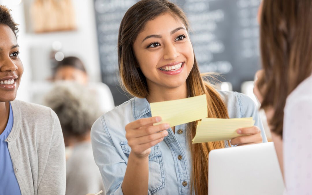 Three female students at table with index cards practicing a computational thinking activity