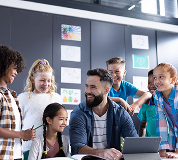 Male teacher with elementary-age students surrounding him as he shows them how to use AI effectively on a tablet