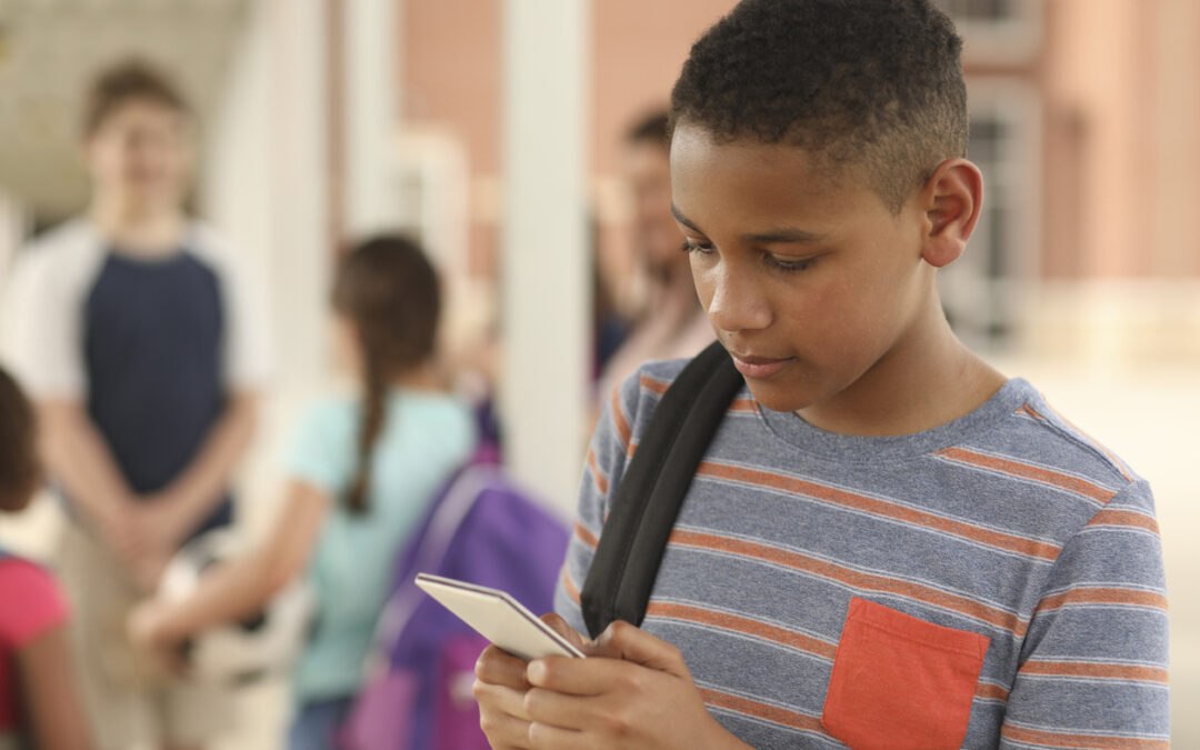 Male junior high student on phone using digital citizenship to reduce online threats