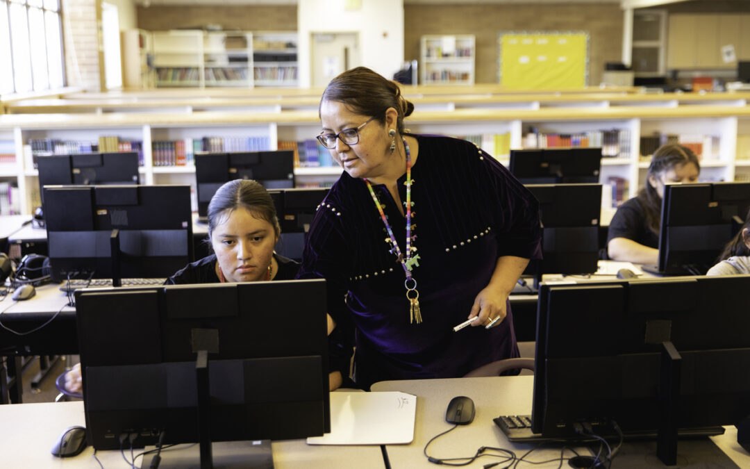 Teacher teaching digital literacy skills in library computer lab